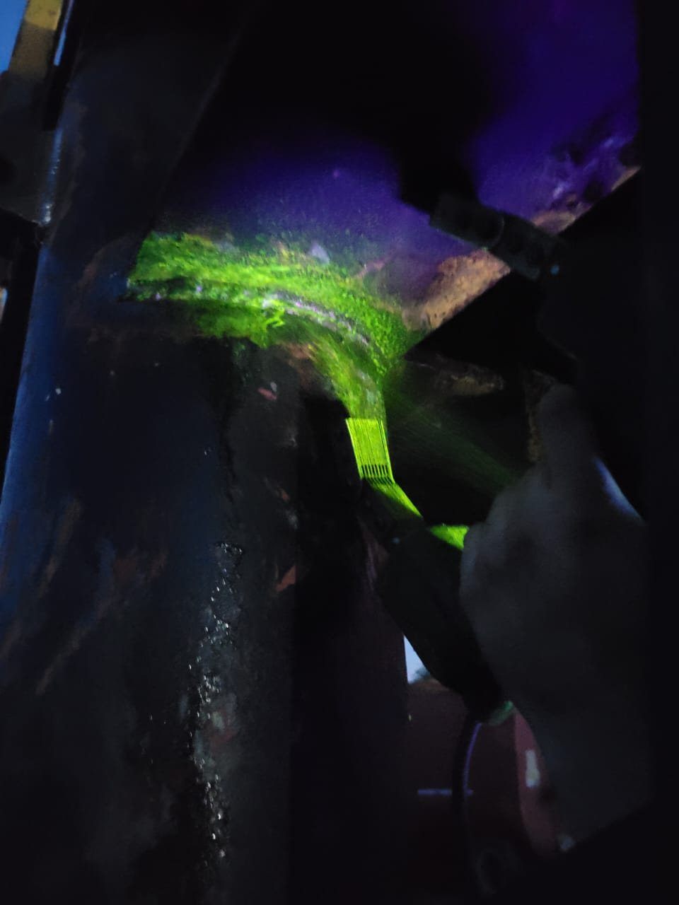 Indicación fluorescente verde revelada bajo luz ultravioleta durante una inspección por partículas magnéticas húmedas